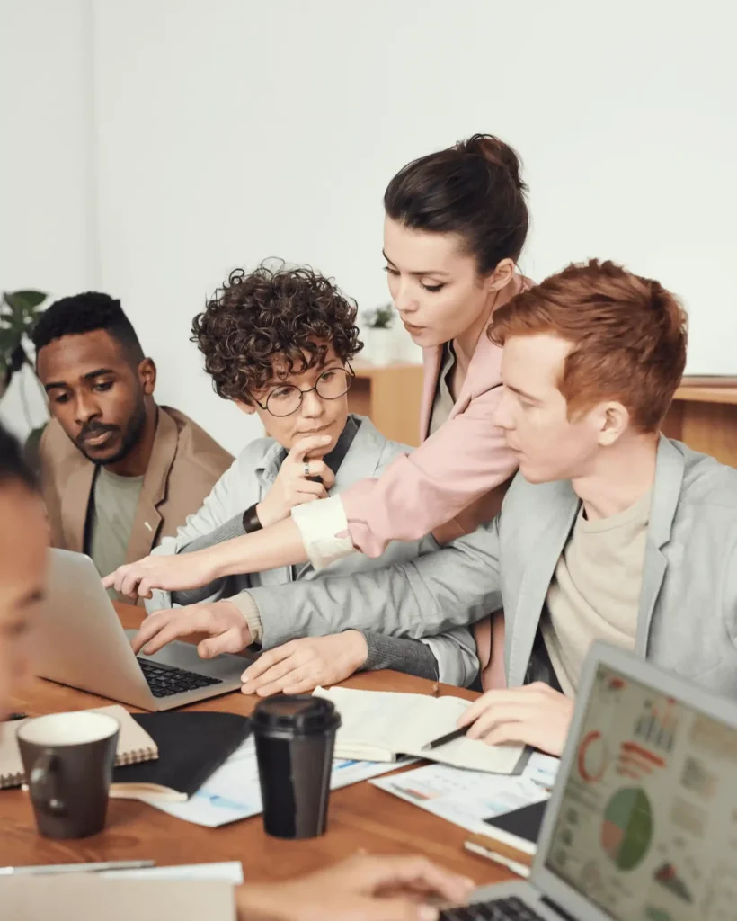 Airline colleagues discussing strategy around laptops and documents in an office setting