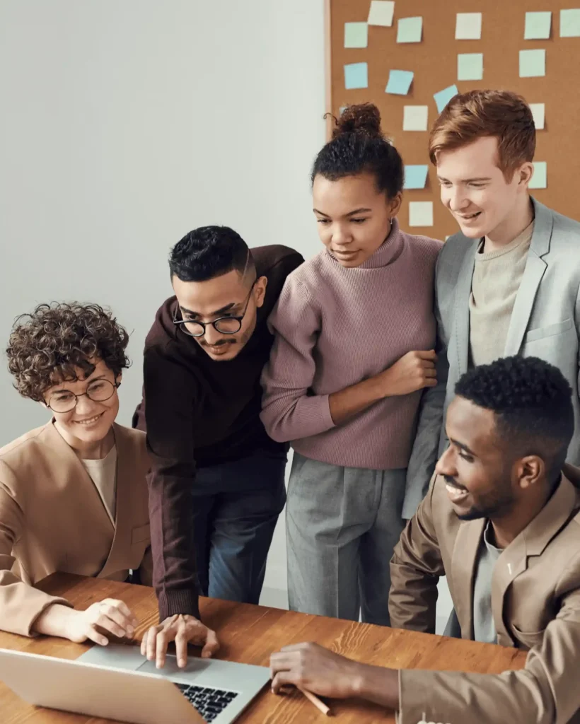 A group of airline colleagues gathered around a laptop during a collaborative team meeting